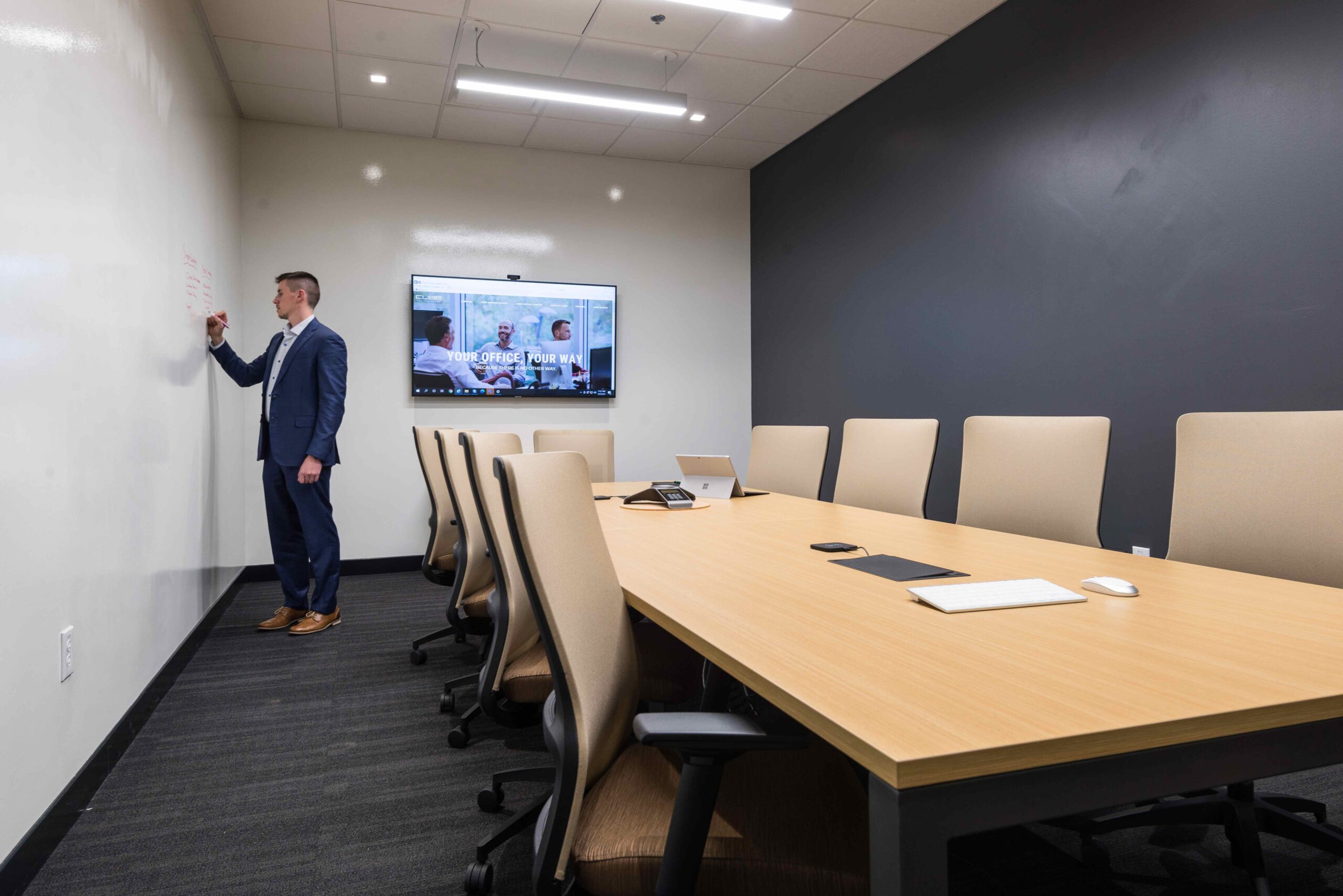 Dallas Meeting Space. Conference room table shares space for 9 people, space includes a TV and whiteboard.