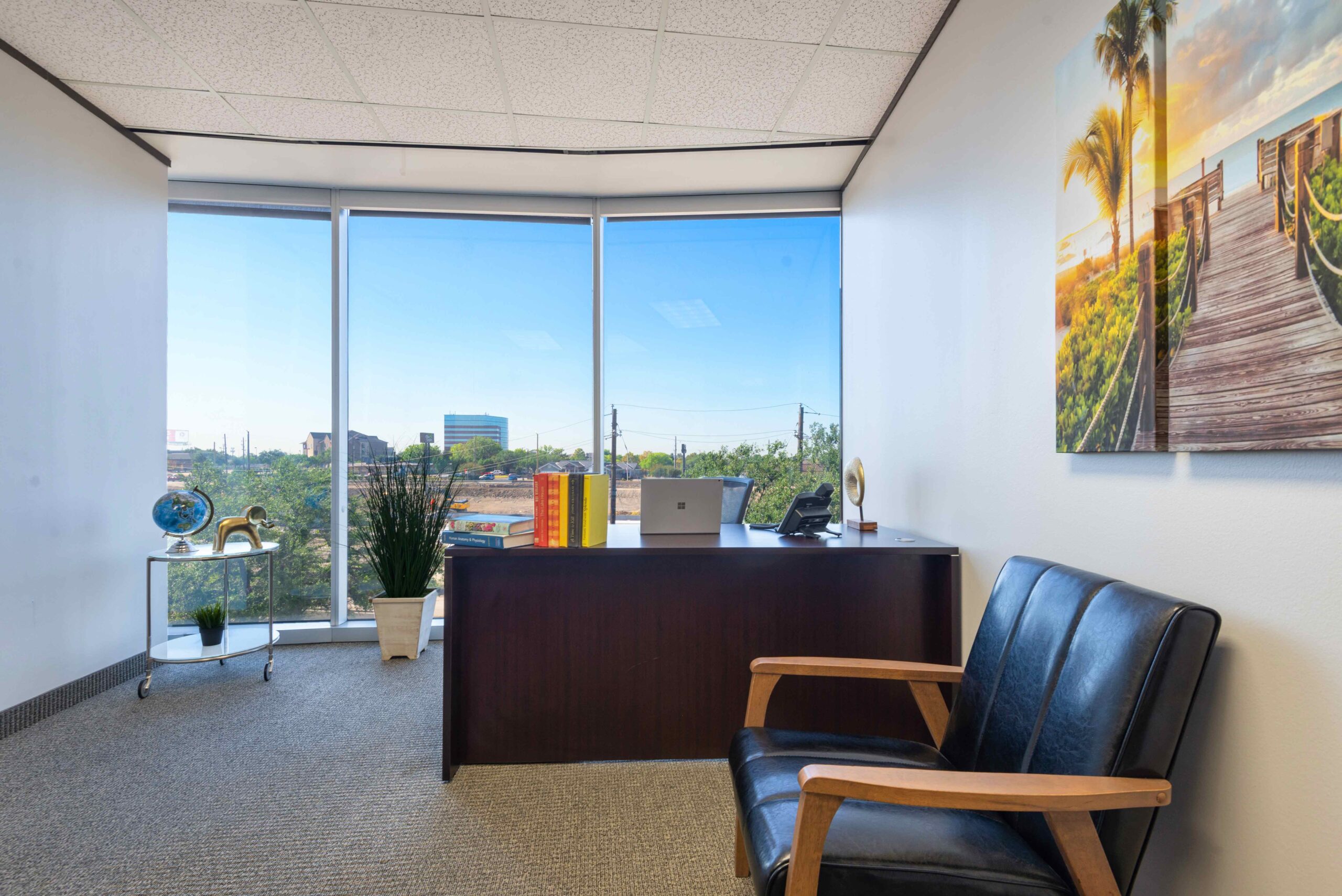 Office space in North Dallas with desk, futon, floor to ceiling windows and natural light.